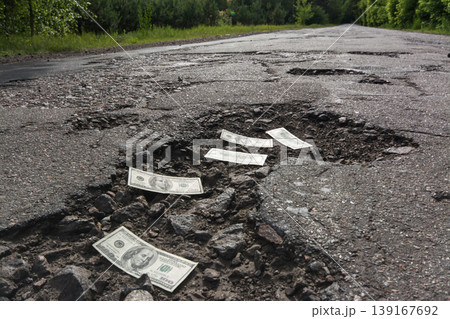 Dollar bills in the potholes on road 139167692