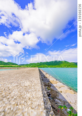 石垣島　青空と緑の山並みに囲まれた船越漁港の防波堤 139168156