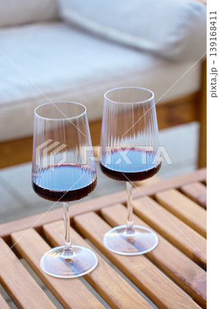 Two glasses with red wine stand on a wooden table outdoors Two glasses with red wine stand on a wooden table outdoors 139168411