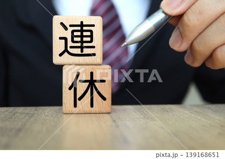 連休と書かれた木製ブロック。ペンを持つビジネスマンの手。休暇計画のイメージ 連休と書かれた木製ブロック。ペンを持つビジネスマンの手。休暇計画のイメージ 139168651