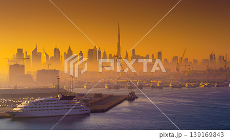 Dubai, United Arab Emirates - Jan 12 2024, Panoramic view of downtown Dubai skyscrapers, with Burj Khalifa, at dawn in a haze, with port and ship on foreground, Dubai, United Arab Emirates Dubai, United Arab Emirates - Jan 12 2024, Panoramic view of downtown Dubai skyscrapers, with Burj Khalifa, at dawn in a haze, with port and ship on foreground, Dubai, United Arab Emirates 139169843