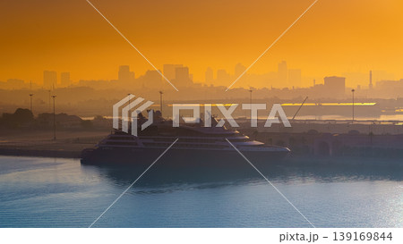 Dubai, United Arab Emirates - Jan 12 2024, Panoramic view of the port, a luxury yacht is moored at the marina, at dawn in haze, silhouettes of buildings in background Dubai, United Arab Emirates   139169844