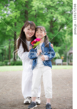 新緑背景母の日にカーネーションを持つ親子(母娘)の笑顔カメラ目線「いつもありがとう!」全身縦 新緑背景母の日にカーネーションを持つ親子(母娘)の笑顔カメラ目線「いつもありがとう!」全身縦 139171598