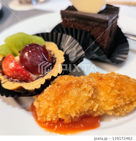 A plate featuring a dessert with slices of srikaya fruit, strawberries and grapes along with a piece of cake and chicken nuggets, displays a delicious culinary dish A plate featuring a dessert with slices of srikaya fruit, strawberries and grapes along with a piece of cake and chicken nuggets, displays a delicious culinary dish 139172462