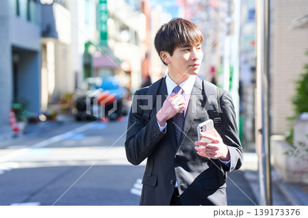 スマホ片手に街中を歩く若い日本人ビジネスマン スマホ片手に街中を歩く若い日本人ビジネスマン 139173376