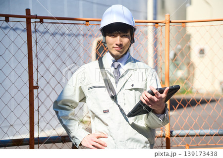 タブレットを手に持ち建設現場の状況を確認する男性現場監督 タブレットを手に持ち建設現場の状況を確認する男性現場監督 139173438