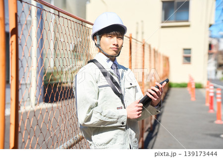 タブレットを手に持ち建設現場の状況を確認する男性現場監督 タブレットを手に持ち建設現場の状況を確認する男性現場監督 139173444
