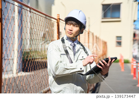 タブレットを手に持ち建設現場の状況を確認する男性現場監督 タブレットを手に持ち建設現場の状況を確認する男性現場監督 139173447