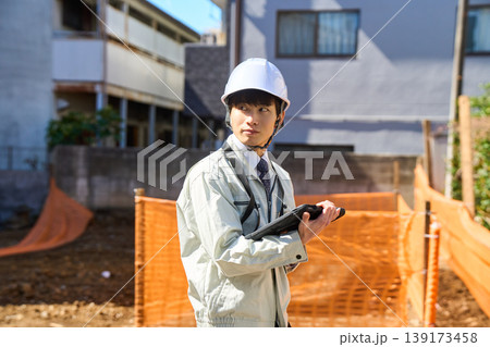 タブレットを手に持ち建設現場の状況を確認する男性現場監督 タブレットを手に持ち建設現場の状況を確認する男性現場監督 139173458