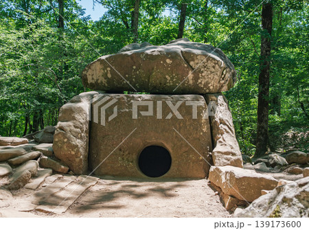 Prehistoric megalithic tomb made of massive stone blocks hidden deep within a vibrant summer forest Prehistoric megalithic tomb made of massive stone blocks hidden deep within a vibrant summer forest 139173600