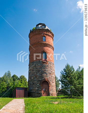 Historic brick and stone water tower rises above green grass under a bright blue sky Historic brick and stone water tower rises above green grass under a bright blue sky 139173633