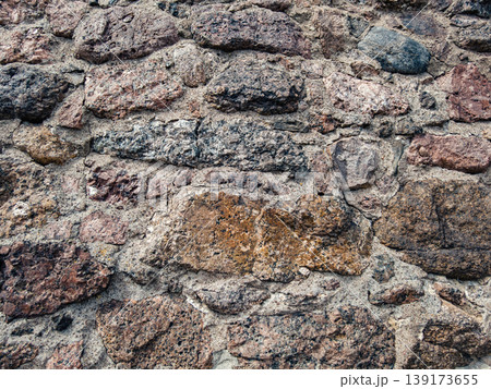 Rough texture of an ancient stone wall showing varied natural colors and weathered mortar outdoors Rough texture of an ancient stone wall showing varied natural colors and weathered mortar outdoors 139173655