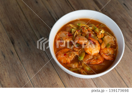 Close up Thai sour curry with shrimp and sesbania flowers in rich orange broth spicy and tangy flavor traditional cuisine served in bowl on wooden table Close up Thai sour curry with shrimp and sesbania flowers in rich orange broth spicy and tangy flavor traditional cuisine served in bowl on wooden table 139173698