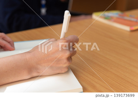 Close up hand writing in notebook with pen on wooden desk natural light workspace focus learning study note taking and productivity concept clean background Close up hand writing in notebook with pen on wooden desk natural light workspace focus learning study note taking and productivity concept clean background 139173699