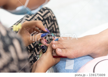 Close up of pedicure session with technician applying nail polish on client toes showing beauty care hygiene relaxation and professional salon service Close up of pedicure session with technician applying nail polish on client toes showing beauty care hygiene relaxation and professional salon service 139173809