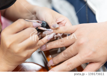 Close up of manicure session with technician applying gel polish on fingernails showing beauty care hygiene precision and professional salon service for healthy stylish hands Close up of manicure session with technician applying gel polish on fingernails showing beauty care hygiene precision and professional salon service for healthy stylish hands 139173811