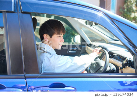 自動車の運転席で笑顔で前を向く作業着姿の若い日本人男性 139174034
