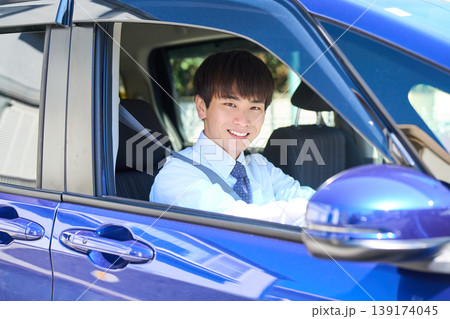 営業車の運転席から窓の外を見て微笑む若い日本人ビジネスマン 営業車の運転席から窓の外を見て微笑む若い日本人ビジネスマン 139174045