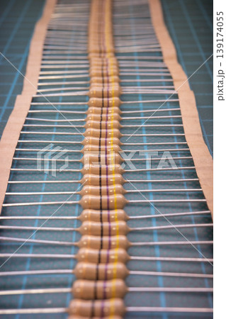 Aligned through-hole resistors on cutting mat electronics background Aligned through-hole resistors on cutting mat electronics background 139174055