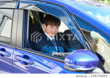 営業車の運転席から窓越しにカメラを見つめる若い日本人ビジネスマン 139174064