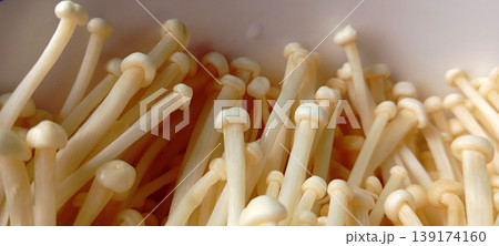 A group of Enoki mushrooms (Flammulina velutipes), also known as golden needle mushrooms. A group of Enoki mushrooms (Flammulina velutipes), also known as golden needle mushrooms. 139174160