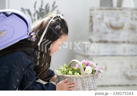 ランドセルを背負って花の入ったカゴを眺める日本人の女の子 139175103