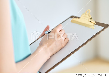 クリップボードにペンで書き込む手元 139175161