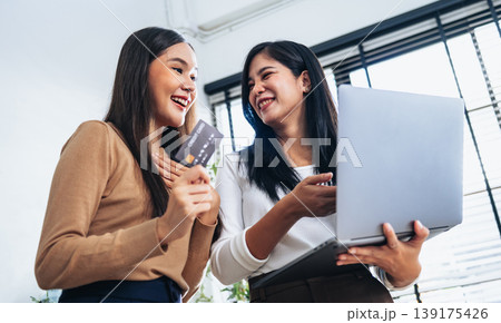 Two women smile together, one holding a credit card 139175426