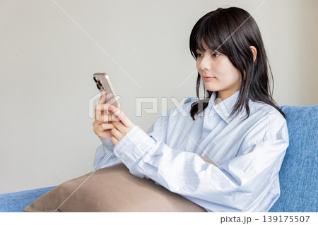 ソファに座ってスマホを操作する女性 139175507