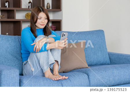 ソファーでスマホを使う若い女性 ソファーでスマホを使う若い女性 139175523