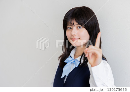 指を立ててポイントを示す笑顔の女子学生・コピースペースあり 139175656