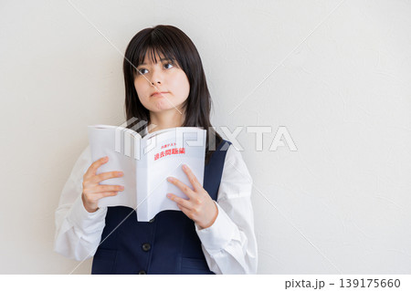 参考書を持って考える女子学生・勉強と受験イメージ(コピースペースあり) 参考書を持って考える女子学生・勉強と受験イメージ(コピースペースあり) 139175660