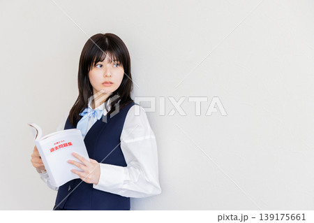 参考書を持って考える女子学生・勉強と受験イメージ(コピースペースあり) 参考書を持って考える女子学生・勉強と受験イメージ(コピースペースあり) 139175661