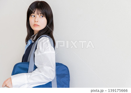 通学バッグを持って振り返る女子学生・登下校イメージ（コピースペースあり） 139175666