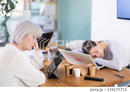 Tired elderly and adult female colleagues fall asleep while working 139175753