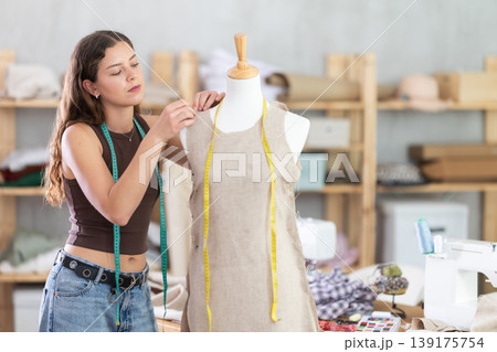 Young female dressmaker working with mannequin in sewing workshop Young female dressmaker working with mannequin in sewing workshop 139175754