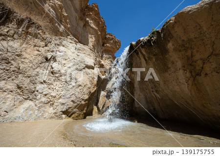Small waterfall cascading into serene pool within oasis of Tamaqzah, Tunisia, surrounded by rugged cliffs Small waterfall cascading into serene pool within oasis of Tamaqzah, Tunisia, surrounded by rugged cliffs 139175755