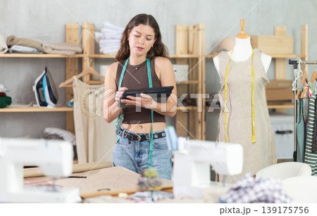 Tailor drawing fashion design on tablet in workshop 139175756