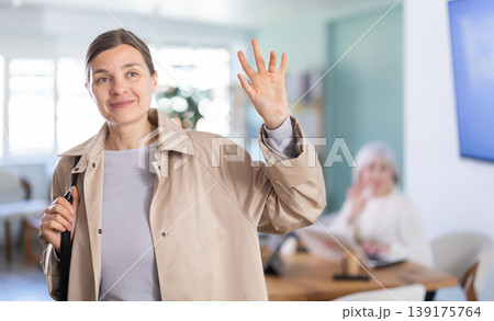 Adult woman leaving office saying goodbye to colleague 139175764