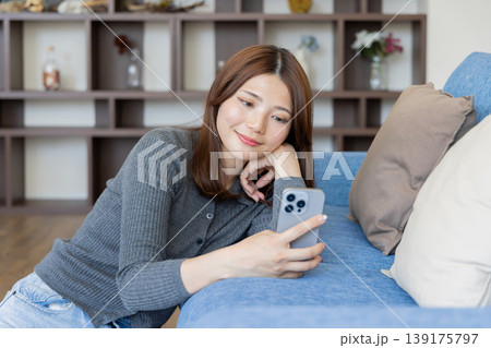 スマートフォンを見るリラックスした女性・自宅ソファでくつろぐライフスタイル 139175797