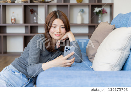 スマートフォンを見るリラックスした女性・自宅ソファでくつろぐライフスタイル 139175798