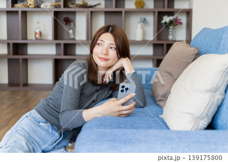 スマートフォンを見るリラックスした女性・自宅ソファでくつろぐライフスタイル スマートフォンを見るリラックスした女性・自宅ソファでくつろぐライフスタイル 139175800