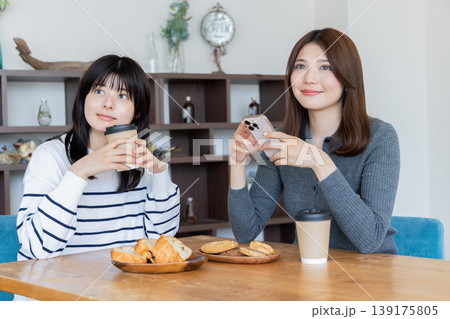 カフェでくつろぎながらスマートフォンを見る女性二人のリラックスタイム 139175805