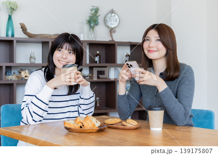 カフェでくつろぎながらスマートフォンを見る女性二人のリラックスタイム カフェでくつろぎながらスマートフォンを見る女性二人のリラックスタイム 139175807