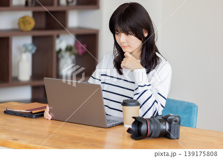 ノートパソコンで作業する若い女性とカメラ 在宅ワーク・クリエイターのライフスタイル 139175808