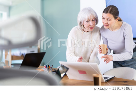 Two businesswomen drink coffee and discuss news during a break in office. Coffee break Two businesswomen drink coffee and discuss news during a break in office. Coffee break 139175863