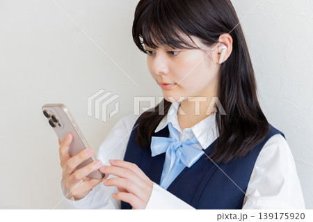 スマートフォンを操作するイヤホン着用の女子高生・デジタルライフと学習イメージ 139175920