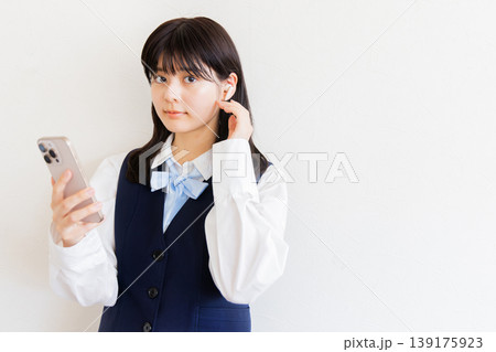 スマートフォンを操作するイヤホン着用の女子高生・デジタルライフと学習イメージ 139175923