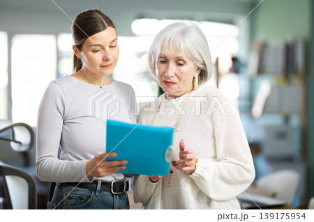 Woman shows elderly colleague documents Woman shows elderly colleague documents 139175954