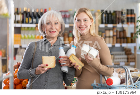 Girl and grandma with dairy products chooses something else, examines labels of cheese and yogurt Girl and grandma with dairy products chooses something else, examines labels of cheese and yogurt 139175964